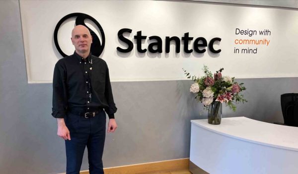 Neil standing agaist the Stantec signage in the office.