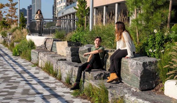People sitting on rocks along a walkway with plantings