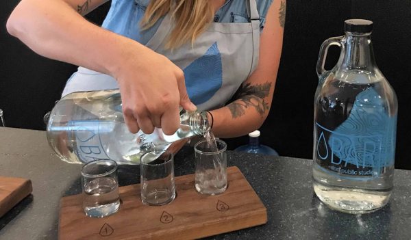 Woman pours three water samples at The Water Bar Minneapolis art project.