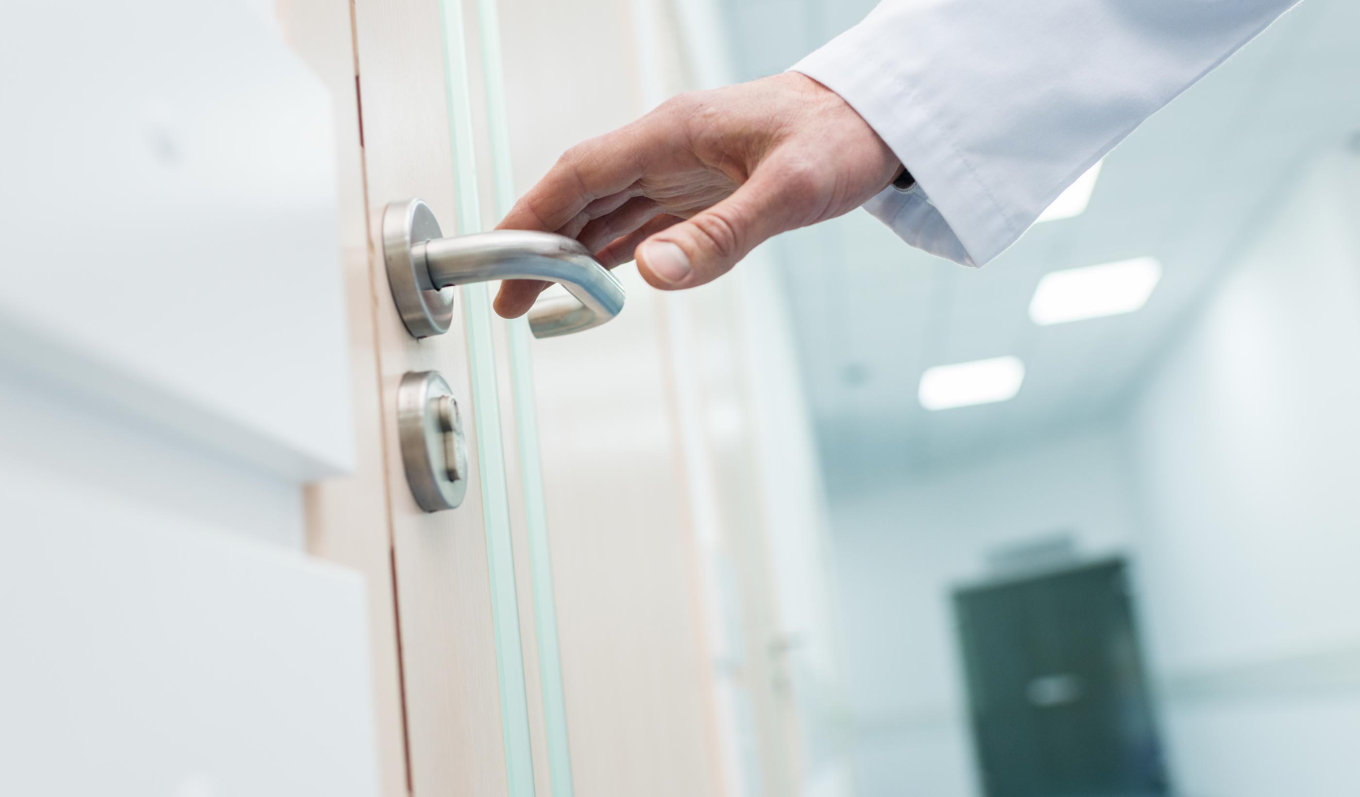 cropped view of male doctor holding door handle in hospital