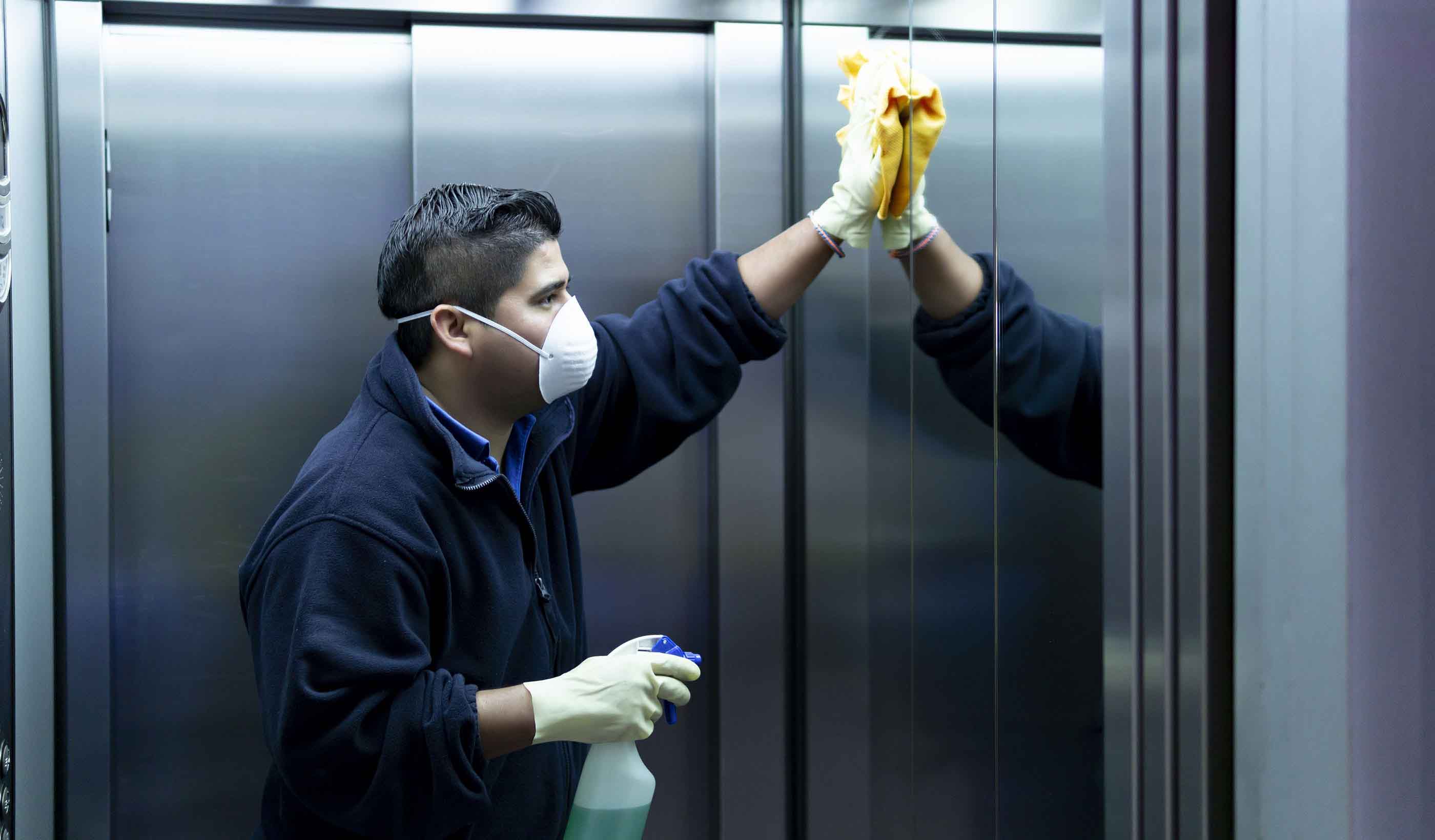 coronavirus. cleaning staff disinfecting elevator to avoid contagion