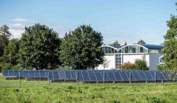 solar panels in a field with a building in the background