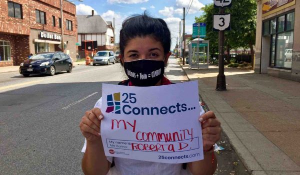 Person in mask holding community connects sign