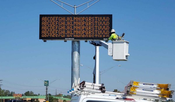 Traveler information sign being installed along a busy roadway.