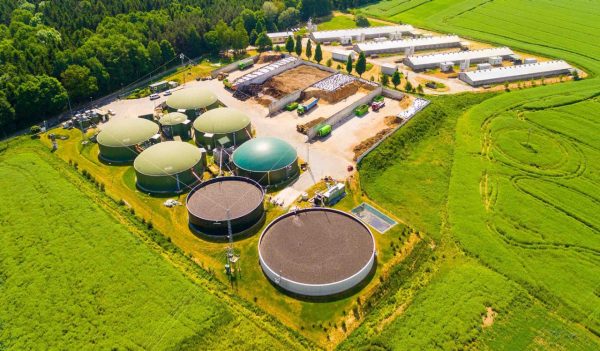 Aerial view over biogas plant and farm in green fields. Renewable energy from biomass. Modern agriculture in Czech Republic and European Union.
