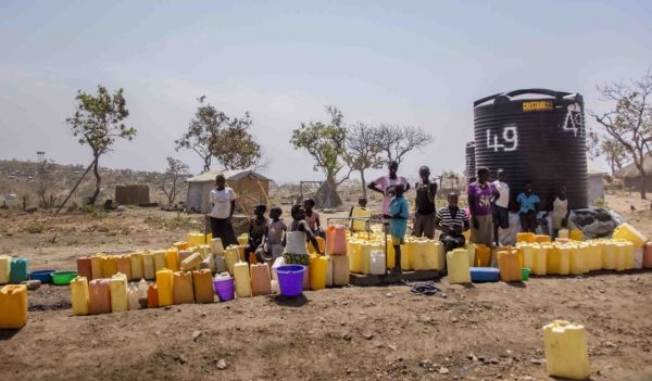 Refugees standing with water containers at Nakivale Refugee Settlement, Uganda