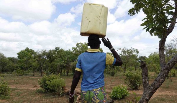 Man carrying water can on his head at refugee settlement.