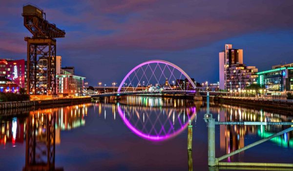 The Clyde Arch lit up at night reflecting off the water.