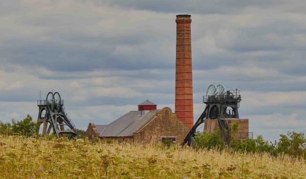 Old coal mine in field with cloudy skies in the background.