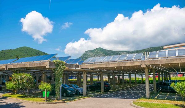 Parking lot covered with a shade structure that has solar panels on it.
