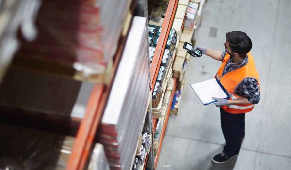 Worker with scanner making review of goods in warehouse