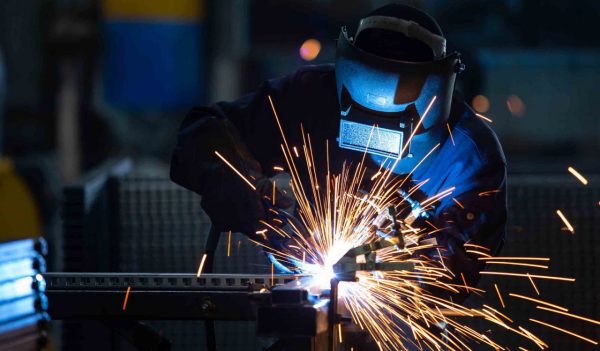 Worker wearing industrial uniform and Welded Iron Mask at Steel welding plants.