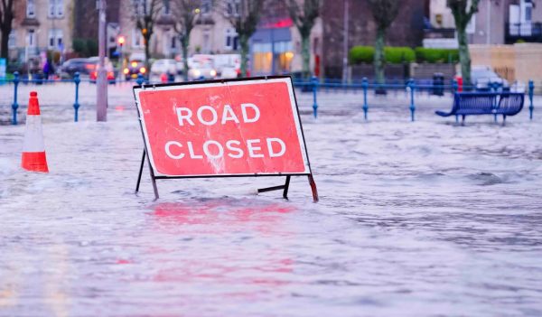 Road flood closed sign under deep water during bad extreme heavy rain storm weather in UK