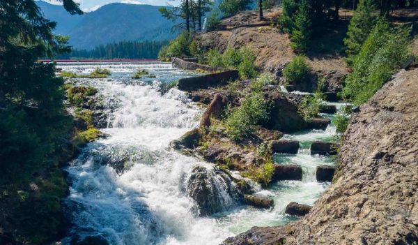 Cascading Clear Lake Falls with Fish Ladder surrounded by rocky cliffs with clouds and a blue sky in summer east of Mount Rainier near Rimrock Lake Yakima County Washington State