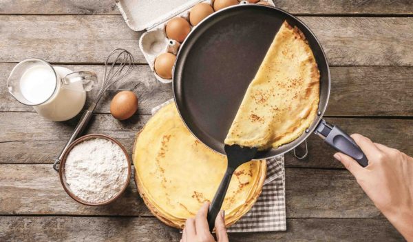 View of person cooking crepes in a frying pan.