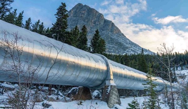 Pipeline running through a remote area in the mountains with snow on the ground.