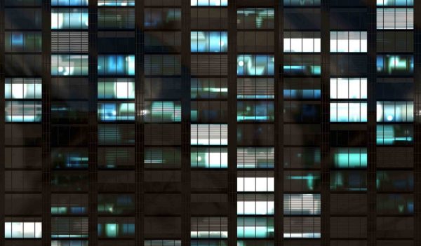 Close up of office building windows at nightm some with lights on.