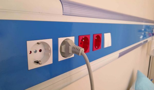 Power cord plugged into electrical outlet on insulated wall in hospital room