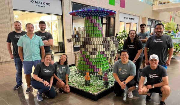 Plano, Text team standing around their can design of a spacechip beaming down. Stantec Staff - Daniel Cahak, John Holland, Natalie Madden, Christopher Zhu, Alicia Thurston, Harsh Chaurasia, Frank Gallegos, Al Hernandez, Jonah Sendelbach