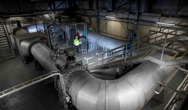 Interior mechanical room at water treatment plant with large piping.