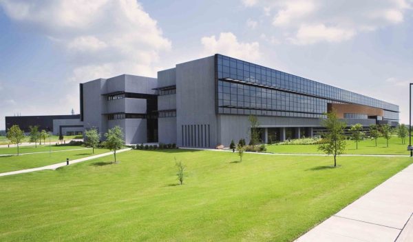 Building exterior - low building with glass window front, surrounded by green grass lawn.