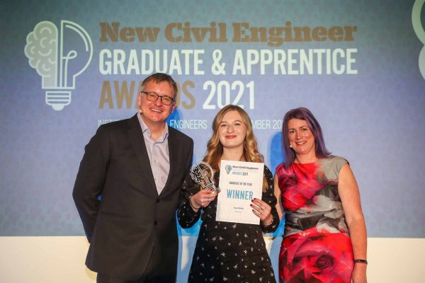 Photograph of Lucy Ashen collecting her NCE Graduate of the Year Award trophy and certificate, stood with two other people