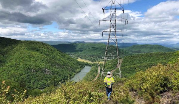 Staff member walking along a mountain path with over transmission lines