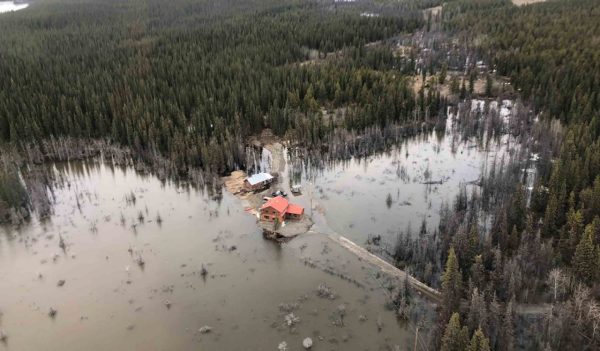 Aerial view of a house surrounded by a flood in a remote area.