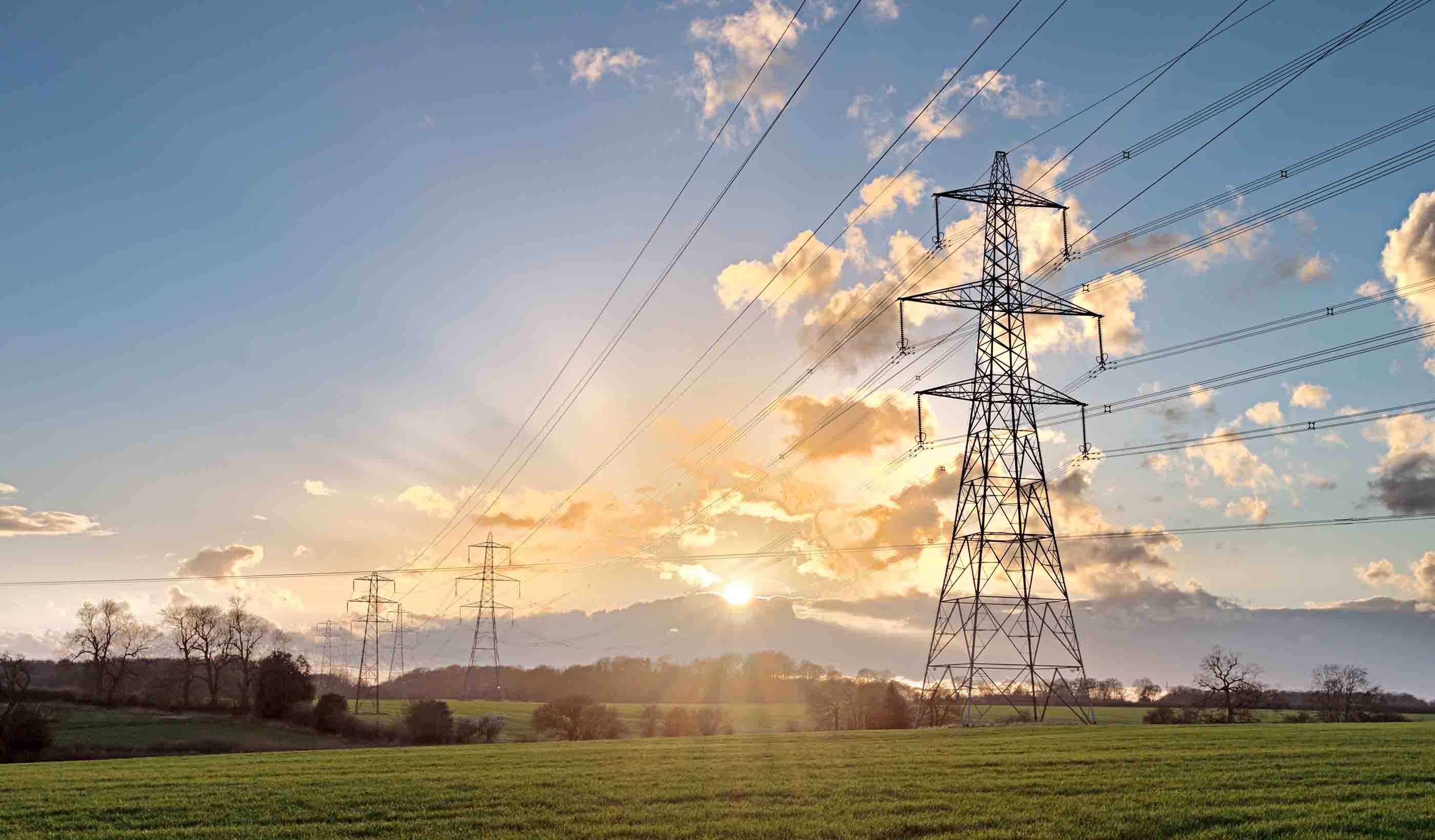 Transmission tower with sun and clouds