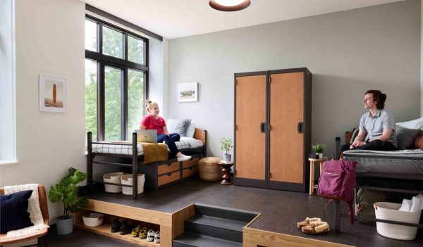 Interior student dorm room showing an elevated platform with beds and a wardrobe in the  middle.