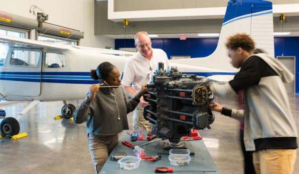 teacher and students working on engine, plane