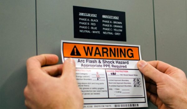 Stock image of hands placing hazard/warning sticker on equipment