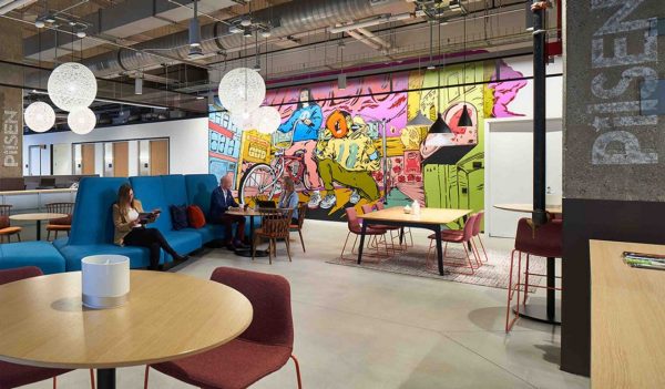 Employee lounge area with tables and a colorful wall mural