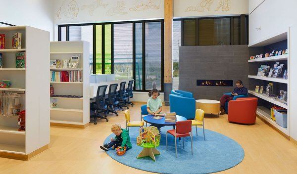 Waiting area with seating for adults and play area for children including bookshelves and activity table.