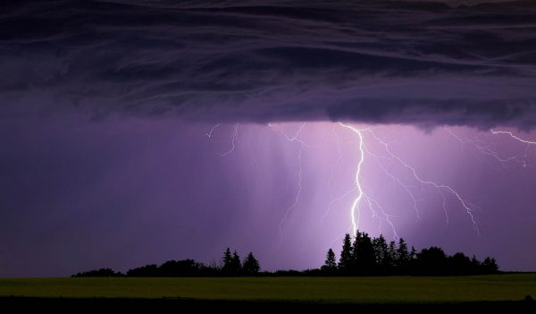 Lighting bolt coming down from sky with purple haze in background.