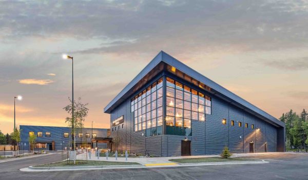 Exterior building and parking lot with plantings lit up at dusk
