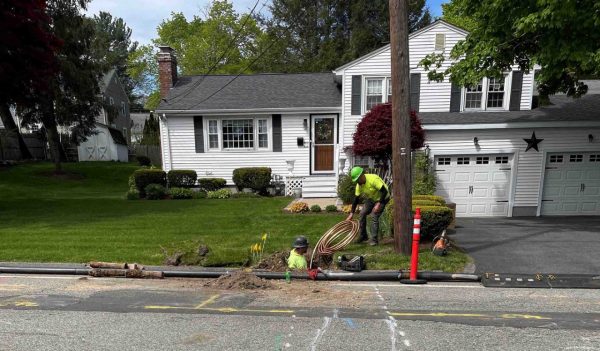 Construction workers replacing a pipeline on a residential street.