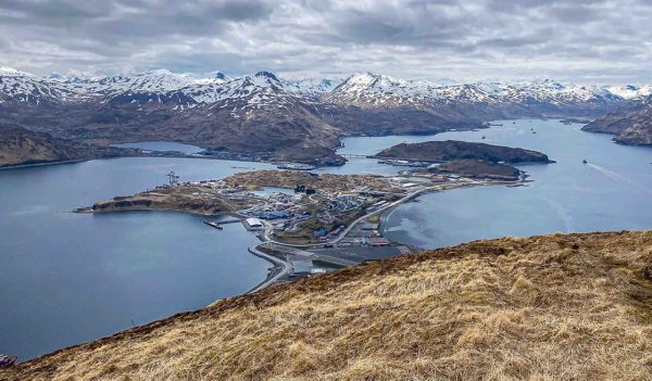 Panoramic aerial view of Unalaska Island with airport, port, and mountains, Alaska Remote Aleutian Island town of Unalaska with harbor and snowy peaks. 